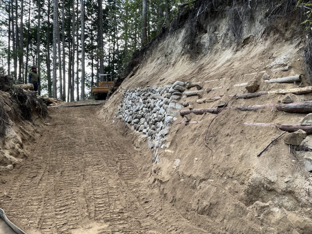 施工後の作業道と、山側の石積みおよび木組みの土留め