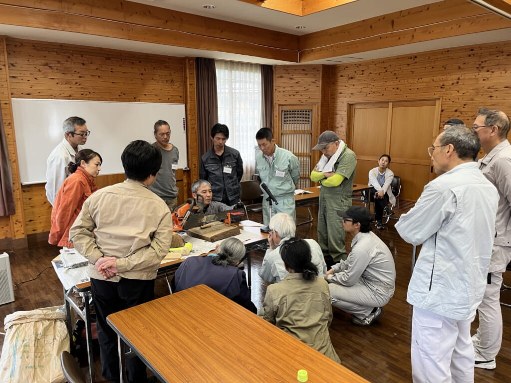 チェーンソーを囲んで点検と整備の方法を学ぶ受講者
