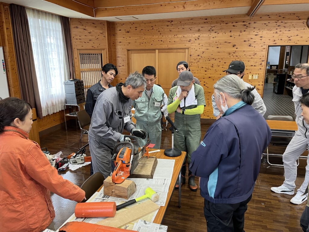 チェーンソー取扱特別教育で実機の説明を聞く上田芳行さん