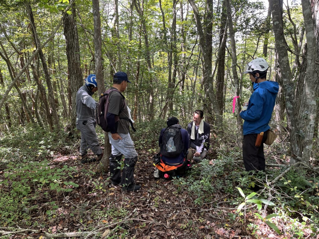 山頂付近で地図とGPSを確認し、森林作業道のルートを確認する参加者