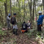 山頂付近で地図とGPSを確認し、森林作業道のルートを確認する参加者