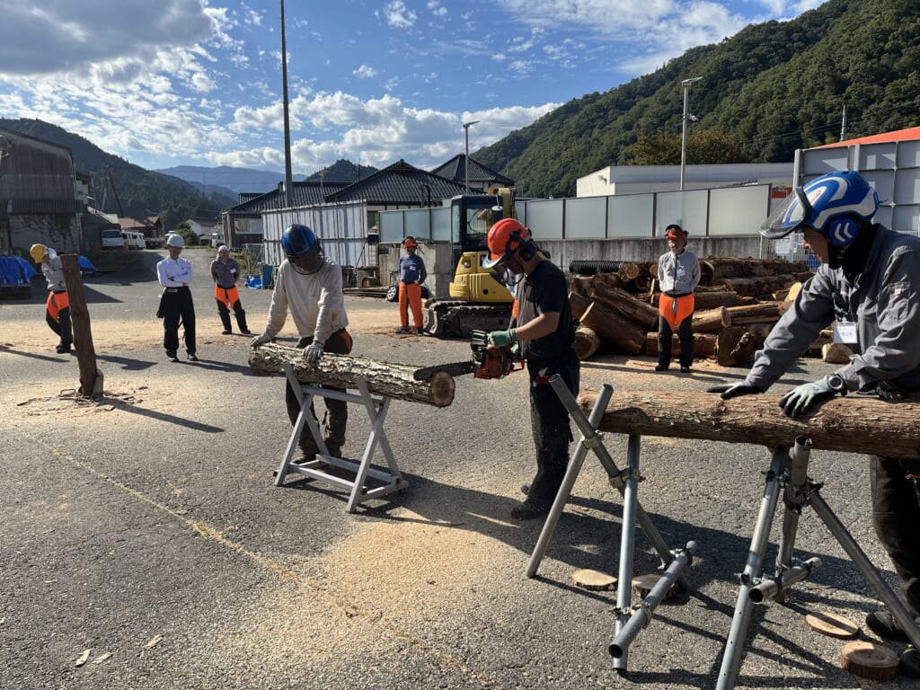 横に置いた丸太をチェーンソーで切断する受講者